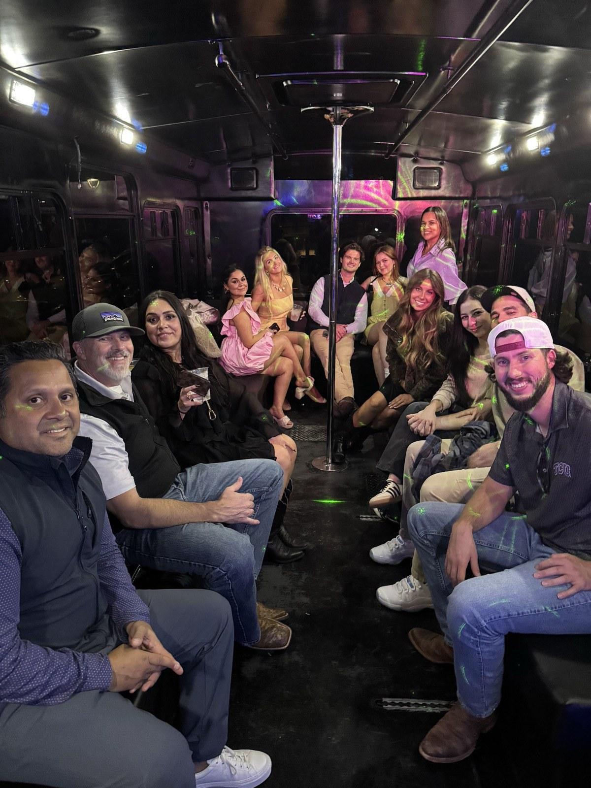 Group dressed up for a formal riding an AUX party bus with neon lighting